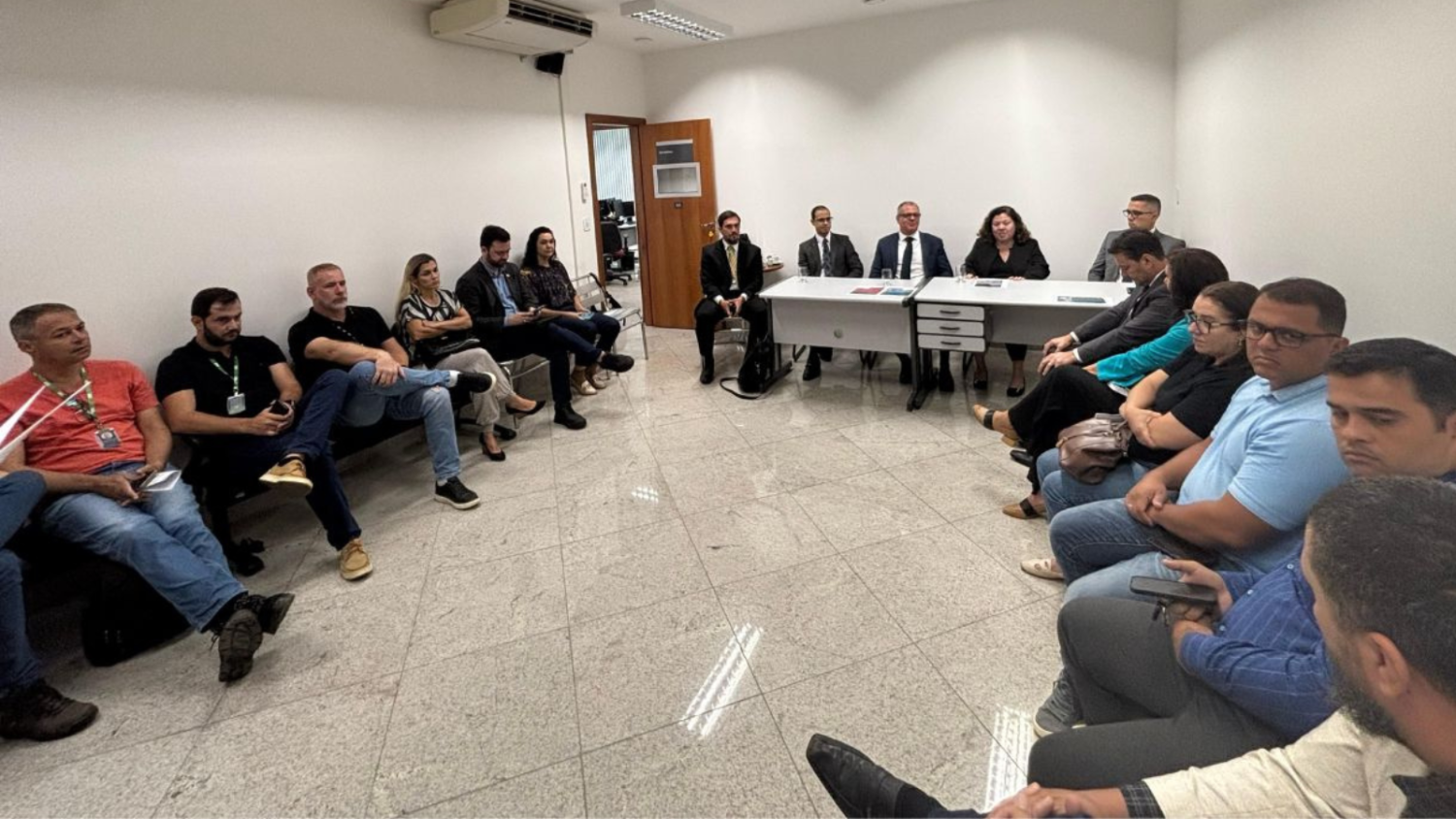 reunião acontecendo numa sala da vara federal, com cerca de 20 homens e mulheres sentados em círculo, ao redor da sala