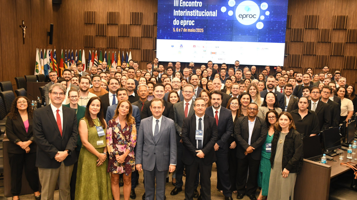 Grupo de aproximadamente 100 homens e mulheres, de pé, participantes, de pé, no auditório, posando para a foto 