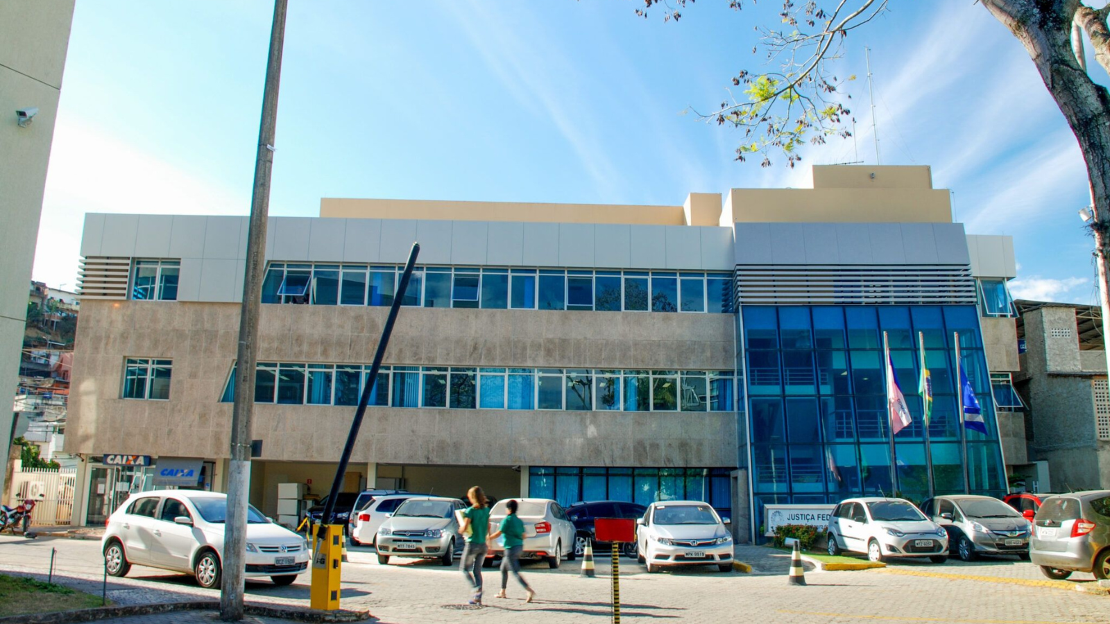 fachada de prédio horizontal de dois andares, com várias janelas de vidro e carros estacionados em frente