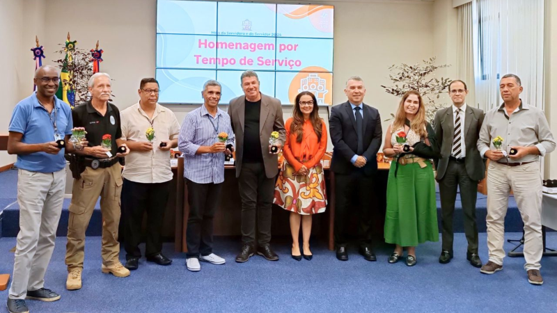 Foto posada de duas mulheres e oito homens. Homenageadas e homenageados mostram caixinhas com os bótons recebidos