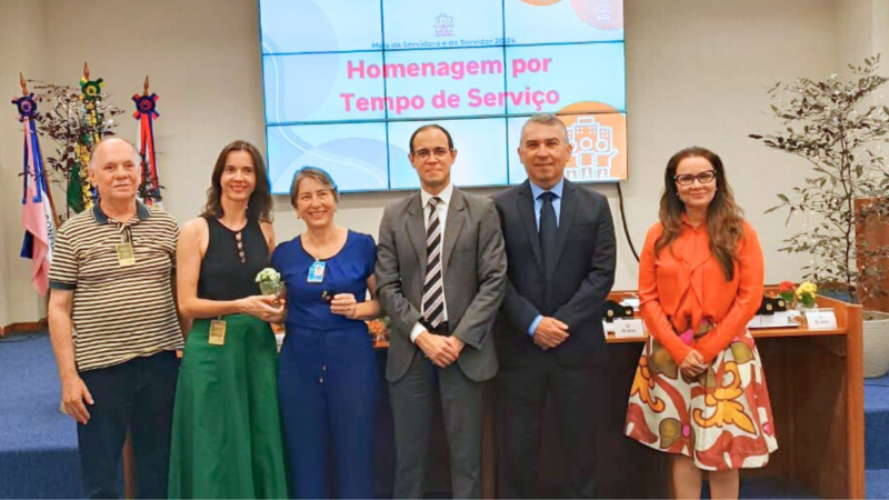 Foto posada de três homens e três mulheres. Os homens estão vestidos em tons sóbrios e as mulheres em tons mais coloridos, como verde, azul e laranja