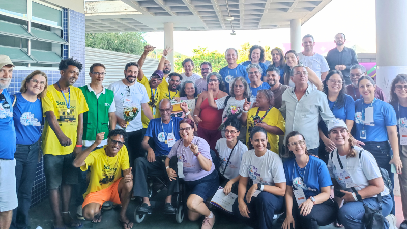 Grupo grande de pessoas posando para a foto, sorrindo, algumas delas com os braços levantados, vibrando por mais um mutirão realizado com sucesso