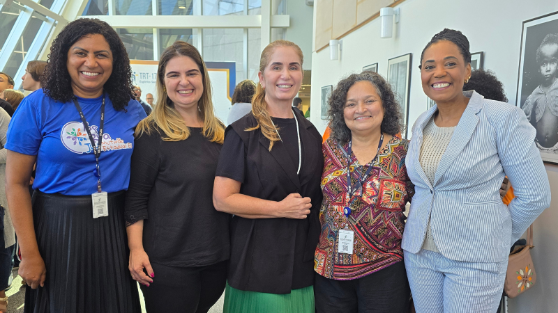 Cinco mulheres sorrindo, sendo três mulheres brancas e duas negras