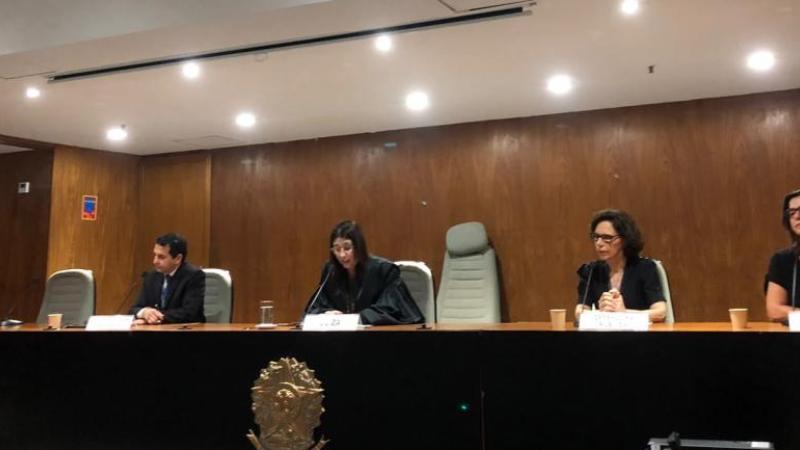 mulheres e homem brancos em mesa sentados lado a lado