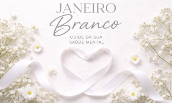 imagem com tons pastéis predominantes. O fundo é branco e nas laterais há arranjos de flores brancas  No meio da imagem, um laço de fita branca em forma de coração. há um texto que diz: "JANEIRO BRANCO CUIDE DA SUA SAÚDE MENTAL"