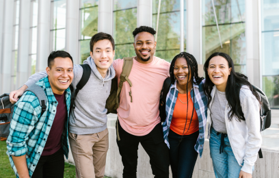 Imagem mostra cinco jovens de etnias diversas abraçados e carregando mochilas escolares 