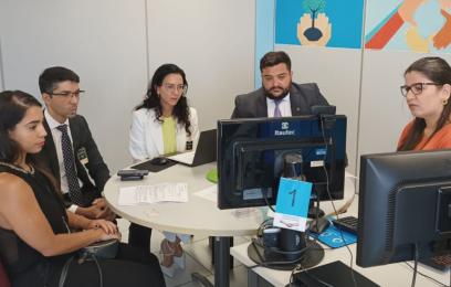 cinco pessoas ao redor de uma mesa (dois homens e três mulheres), olhando para a tela de um computador