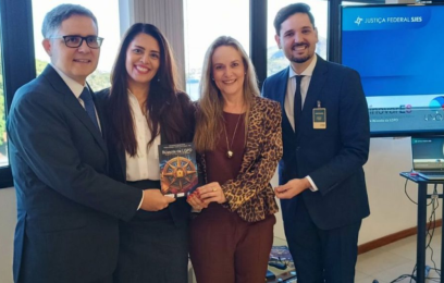 Dois homens e duas mulheres posam para a foto, elas ao centro, com a cartilha nas mãos