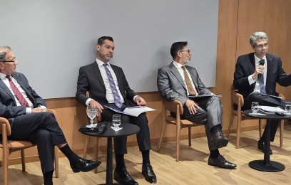 O desembargador federal Guilherme Calmon fala ao microfone, sentado. Ao seu lado, outros três