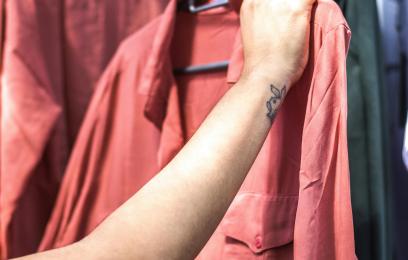 Mulher suspende uma camisa social de cor avermelhada