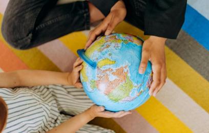 mãos de duas crianças seguram globo terrestre