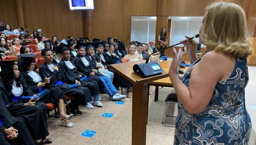 mulher falando em pulpito para jovens em auditório 